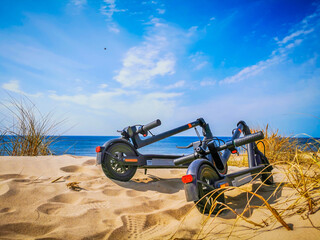 Two electric scooters standing on the sand dunes by the sea