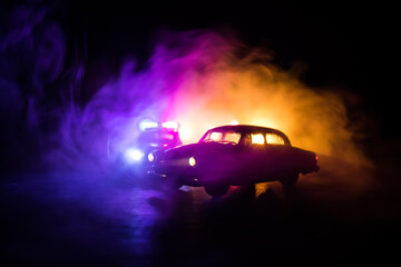 Wall Mural - Police car chasing a car at night with fog background. 911 Emergency response police car speeding to scene of crime.