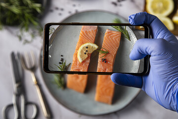 Sticker - Top view of a hand in disposable gloves taking a picture of appetizing salmon fillets on the plate