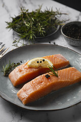 Sticker - Vertical shot of two salmon fillets served on a plate with lemon and rosemary on the table