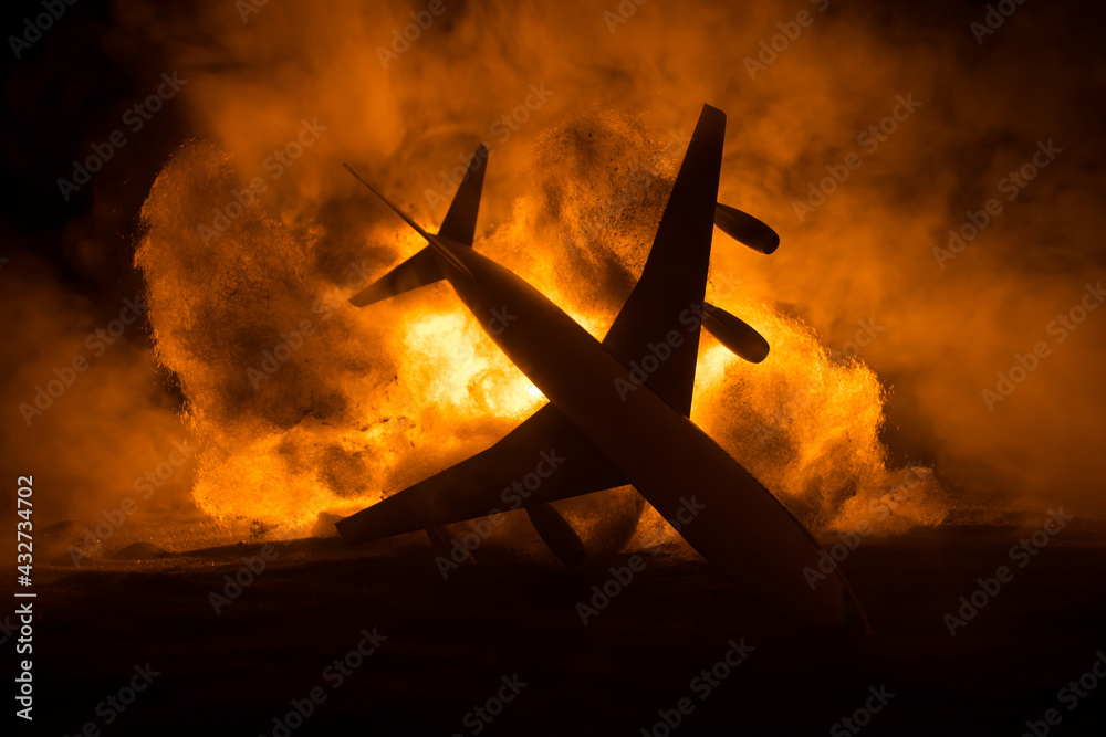 Air Crash. Burning falling plane. The plane crashed to the ground. Decorated with toy at dark fire background. Air accident concept. - obrazy, fototapety, plakaty 