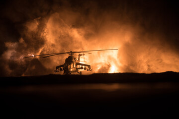 Wall Mural - Silhouette of military helicopter ready to fly from conflict zone. Decorated night footage with helicopter starting in desert with foggy toned backlit. Selective focus. War concept