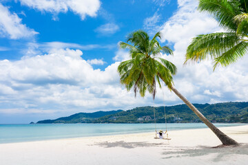 Phuket, Thailand. Tropical beach paradise with beach swing with girl in white shirt. Women relax on swing under coconut palm tree at beautiful tropical beach White sand holiday summer vacation concept