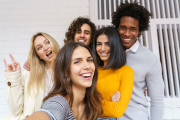 Multi-ethnic group of friends taking a selfie together while having fun outdoors.