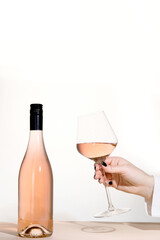 Young woman holding glass of rose wine on white background. Hand with black polish.