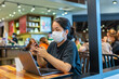 © Quang - Woman wearing mask and using smartphone in cafe