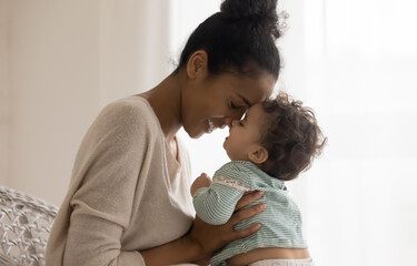 happy young african american mom hug cuddle with little baby kid daughter at home. smiling mixed rac