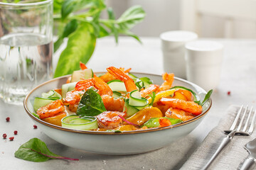 Canvas Print - Lunch table. Salad with grilled prawns, caramelized pears, cucumber and mixed greens. Close-up. Light background.