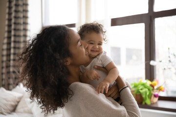 Wall Mural - happy caring african american mother hold in arms cuddle cute little biracial baby daughter, show lo