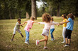 © liderina - Large group of school kids having fun in nature.  Happy kids dancing and holding hands.
