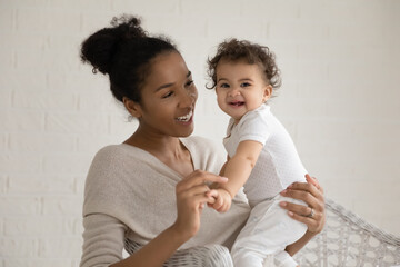 Wall Mural - portrait of happy young african american mother hold in arms play with little newborn baby daughter.