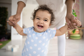 Wall Mural - close up portrait of african american little toddler girl baby laugh learn walking at home with moth