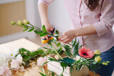 Fototapeta Lawenda - Florist at work: young brunette woman hands making fashion modern composition of different flowers at home