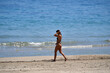 © Frank Middendorf - A sportive young woman in a black bikini walks at the beach of Benidorm-Spain. A woman grabs her hair.