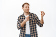 © Cookie Studio - Image of joyful redhead man snap fingers to rhythm of music, dancing with close eyes and satisfied face expression, enjoying party, celebrating success achievement, standing over white background