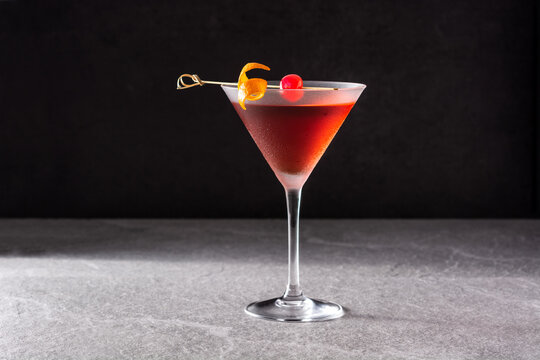 traditional manhattan cocktail with cherry on gray stone