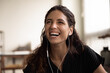 Candid laughter. Headshot of overjoyed millennial latin female wearing wired earphones laughing in good mood showing beautiful even teeth. Carefree young woman having fun listen to funny joke on radio
