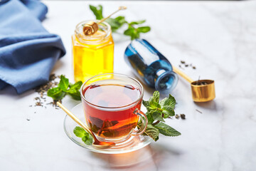 Wall Mural - Black tea in glass transparent mug with mint leaves and honey. Calming and revitalizing tea, anti-stress and relaxation