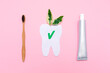 Eco and hygiene. A bamboo toothbrush, toothpaste and cut out tooth of felt with leafs. Flat lay. Pink background. Concept of eco-friendly hygiene objects