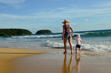 Mother and child are walking along the beach. Mom and baby. Family concept. Sea vacation concept.