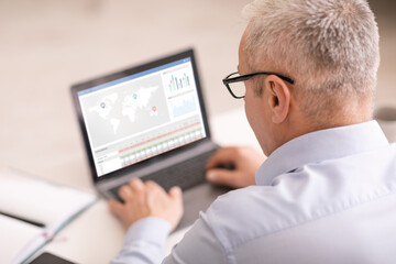Aufkleber - Senior businessman using laptop, checking stock analysis software