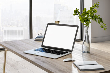 Blank white laptop monitor on wooden table with glass vase and notebook in sunny home office. 3D rendering, mock up
