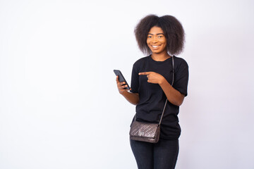 Wall Mural - happy attractive young black woman with a smile on her face gestures to her phone