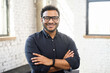 Headshot of skilled hindu male employee standing with arms crossed in modern office, successful confident mixed-race man wearing eyeglasses and smart casual, business portrait of indian entrepreneur
