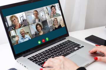 View over businesslady shoulder seated at workplace desk look at computer screen where collage of many diverse people involved at video conference negotiations activity, modern app tech usage concept