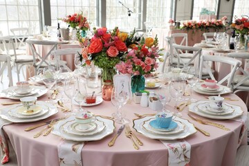 Table set up for bridal shower on bright spring day with flowers in the middle and vintage tea cups on each plate