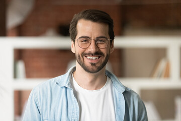 head shot portrait confident smiling bearded businessman in glasses looking at camera, standing in o