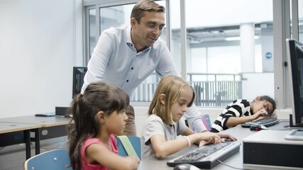 Multiethnic girls doing task on computer science together. Blonde kid typing confidently on keyboard. Male teacher happy with students progress. Digital education concept.