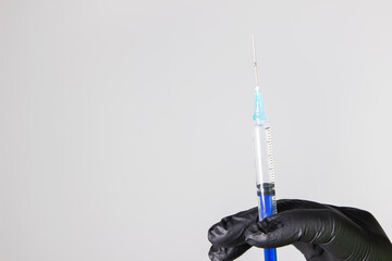 A hand holding a syringe with a dialed vaccine and medicine