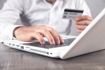 Wall Mural - Businessman using laptop computer and holding credit card.