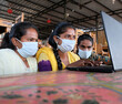 Group of Indian male and female wearing facemask while looking at a laptop