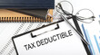 Text Tax Deduction on Office desk table with notebooks, supplies,analysis chart, on white background.