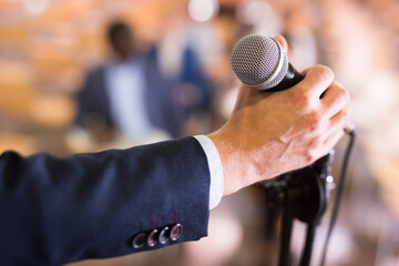 Close up of male hand holding microphone at conference hall