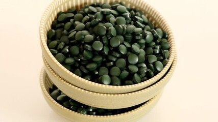 Wall Mural - Spirulina pills close-up. Spirulina algae green tablets in round green cups.Super food.seaweed. Food supplements for a healthy lifestyle