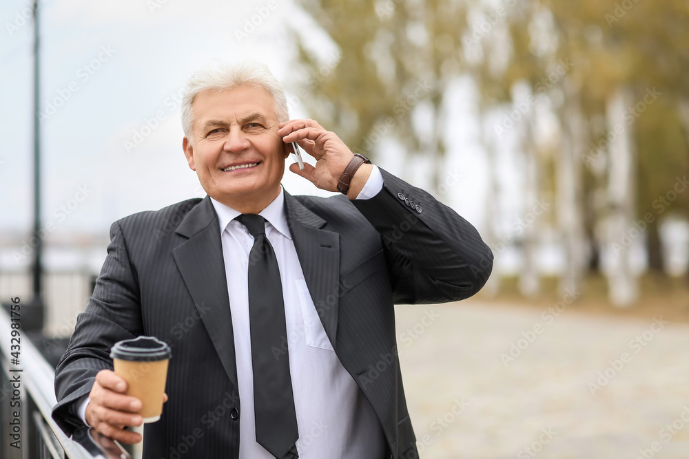 Senior businessman talking by mobile phone outdoors