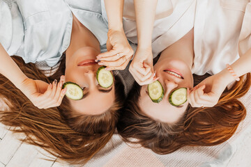 Wall Mural - two girls make homemade face and hair beauty masks. cucumbers for the freshness of the skin around t