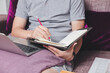 © skarie - A man in casual wear writing on notebook and using laptop while he is working at home office.