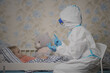 © Azhorov - Female doctor wearing epidemic protective suit talking with little girl patient with coronavirus symptoms during quarantine at home.