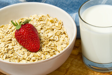 Healthy food. Oat flakes with fresh strawberry in white bowl, wooden background. copy space