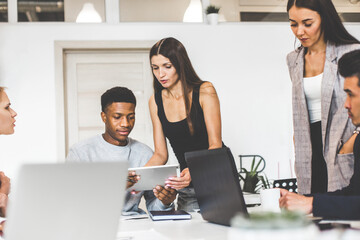 Wall Mural - A team of young office workers, businessmen with laptop working at the table, communicating together in an office. Corporate businessteam and manager in a meeting. coworking.