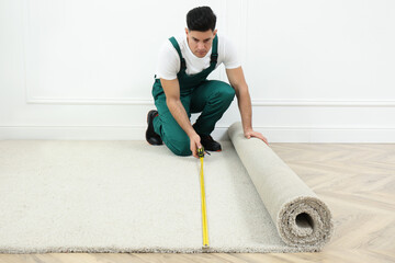 Canvas Print - Worker with measuring tape installing new carpet indoors