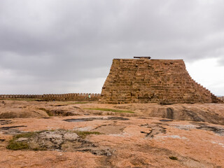 Poster - The stone bastion with a cannon of the ancient Thirumayam Fort on a rocky hill.