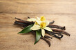 Beautiful vanilla flowers and sticks on wooden table, closeup