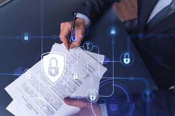 Wall Mural - A businessman in formal wear signing the contract to prevent probability of risks in cyber security. Padlock Hologram icons over the working desk.