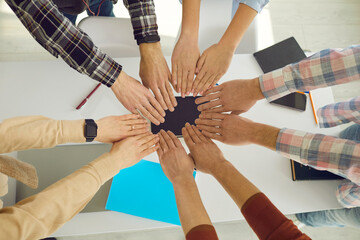 Close up of people's hands, which they fold together so that the circle is formed as a symbol of unity. Students or a young team of startups go to a common goal. Concept of teamwork. Top view.