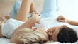 © LIGHTFIELD STUDIOS - young couple kissing and holding hands while lying on bed